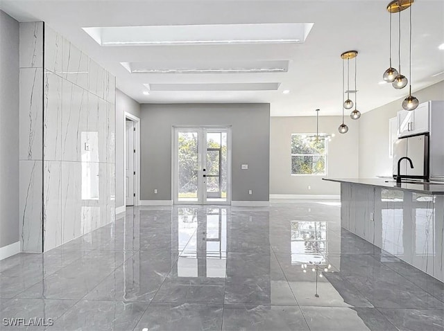 unfurnished living room featuring a wealth of natural light, french doors, and sink