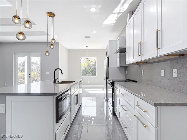 kitchen with stainless steel electric stove, sink, decorative backsplash, built in microwave, and decorative light fixtures