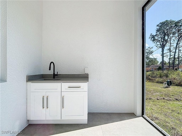 bar featuring dark tile patterned flooring, white cabinetry, and sink