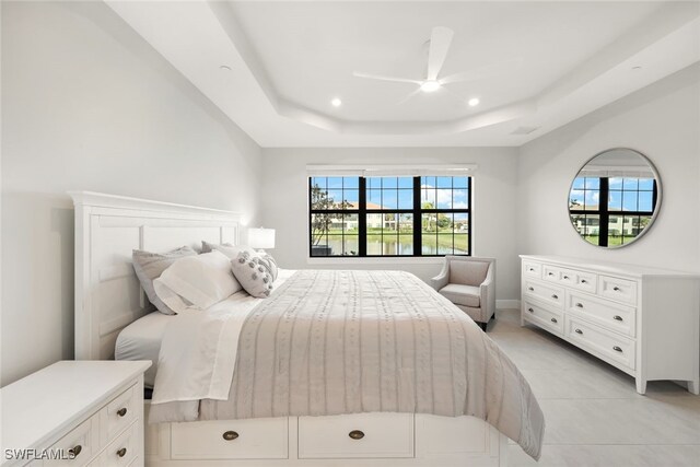 bedroom featuring ceiling fan, light tile patterned flooring, and a raised ceiling