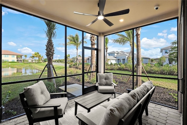 sunroom / solarium featuring ceiling fan, a water view, and a healthy amount of sunlight