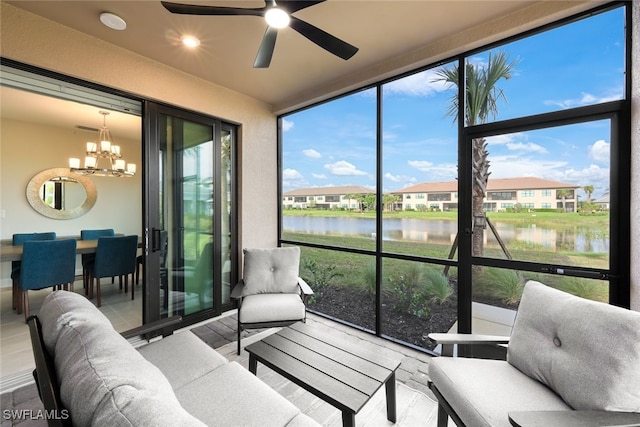 sunroom featuring a water view and ceiling fan with notable chandelier