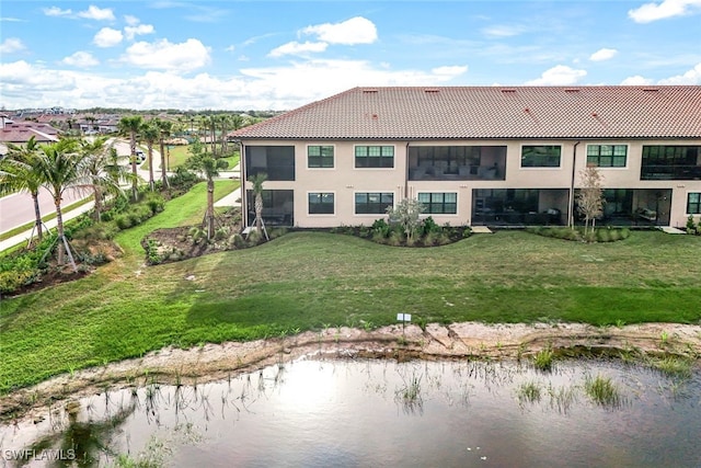 rear view of property with a lawn and a water view