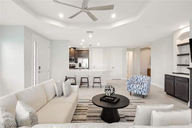 living room with a tray ceiling and ceiling fan