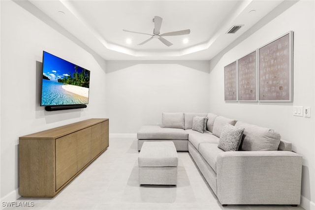 living room with a tray ceiling and ceiling fan