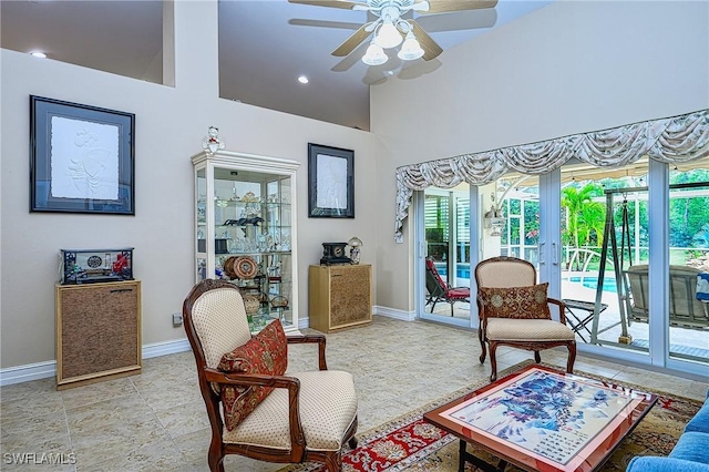 living room featuring ceiling fan and a high ceiling