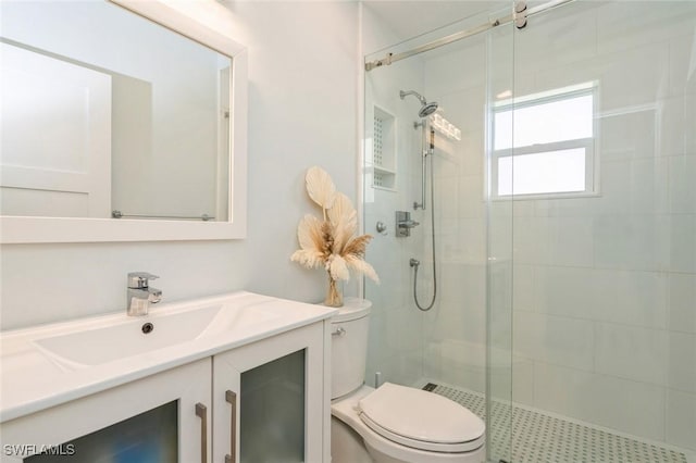 bathroom with vanity, toilet, and a shower with door