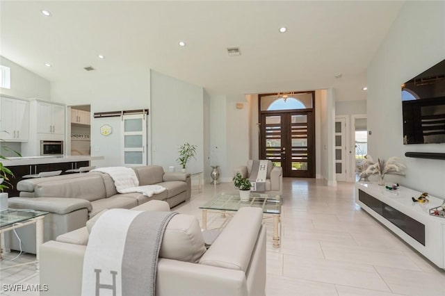 living room with french doors, a barn door, and light tile patterned flooring