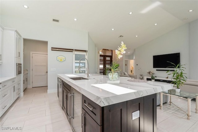 kitchen featuring dark brown cabinets, vaulted ceiling, sink, a barn door, and white cabinets