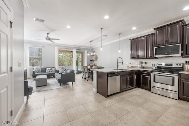 kitchen with pendant lighting, sink, appliances with stainless steel finishes, ornamental molding, and kitchen peninsula