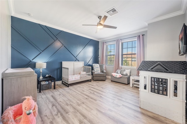 bedroom with a crib, ornamental molding, ceiling fan, and light hardwood / wood-style floors