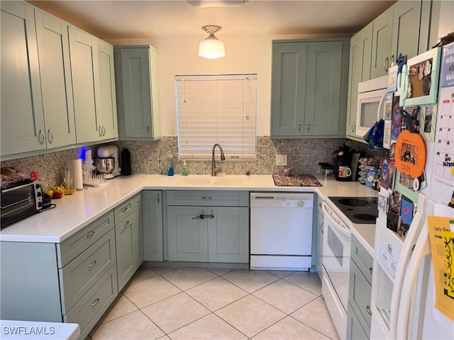 kitchen with decorative backsplash, light tile patterned floors, white appliances, and sink