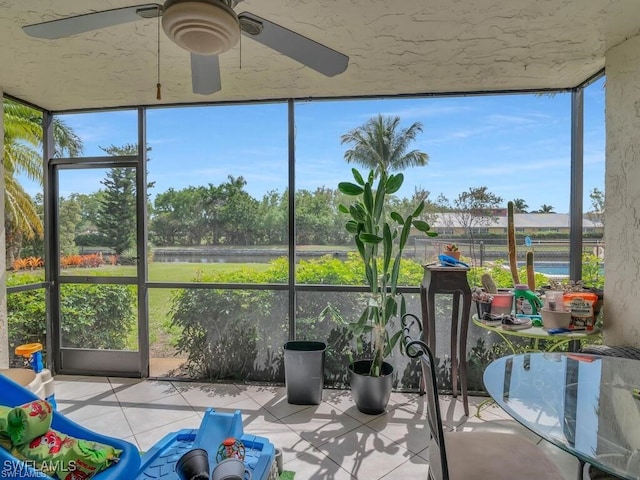 unfurnished sunroom with ceiling fan, plenty of natural light, and a water view