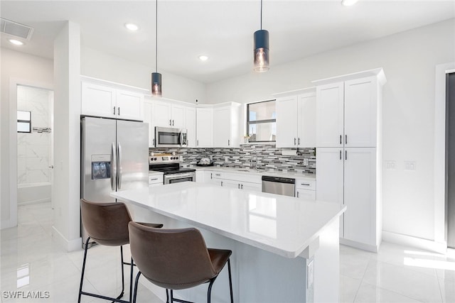 kitchen featuring white cabinetry, a kitchen island, pendant lighting, and appliances with stainless steel finishes