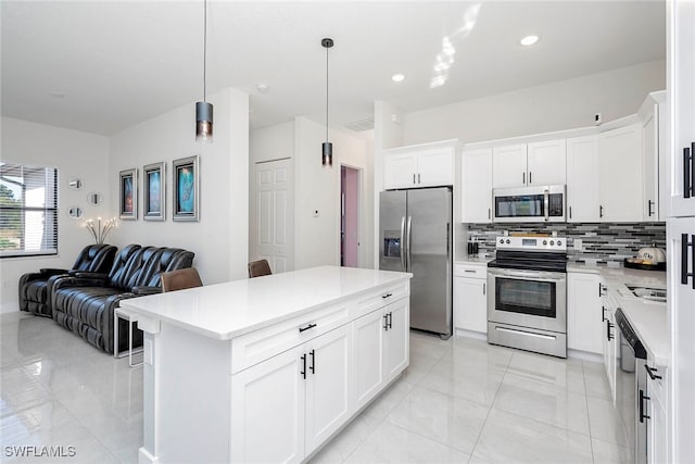 kitchen with decorative backsplash, stainless steel appliances, decorative light fixtures, a center island, and white cabinetry