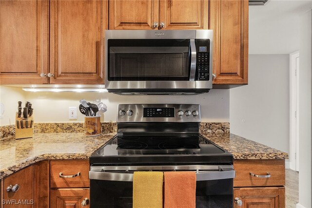 kitchen featuring appliances with stainless steel finishes, light stone counters, and wood-type flooring