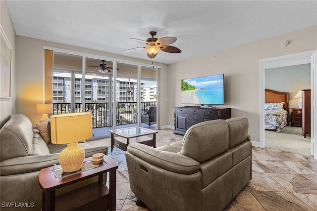 living room featuring ceiling fan and a textured ceiling