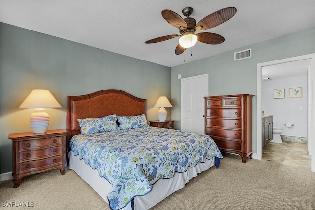 bedroom with ensuite bathroom, ceiling fan, and light colored carpet