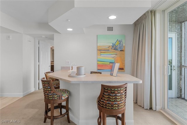 kitchen featuring a breakfast bar area and light carpet