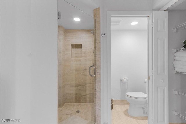 bathroom featuring toilet and a shower with shower door