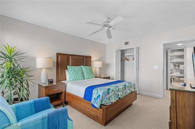 bedroom with a closet, ceiling fan, and light colored carpet