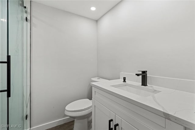 bathroom with vanity, hardwood / wood-style flooring, toilet, and a shower with shower door