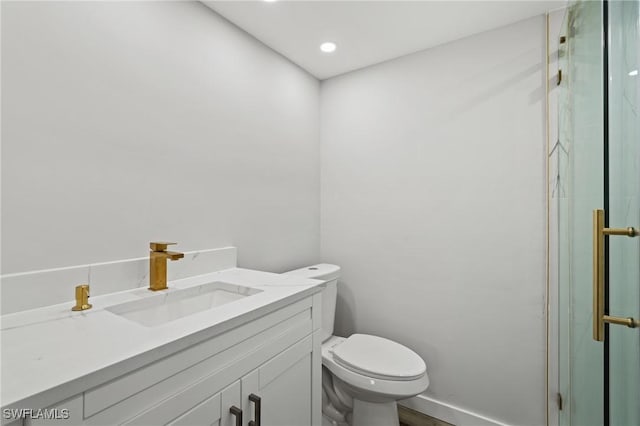 bathroom with vanity, toilet, and a shower with door