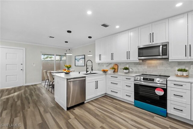 kitchen with kitchen peninsula, white cabinets, and stainless steel appliances