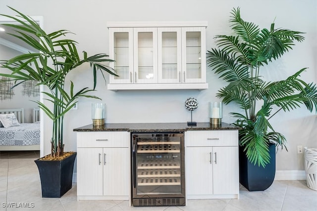 bar featuring white cabinets, dark stone countertops, and beverage cooler