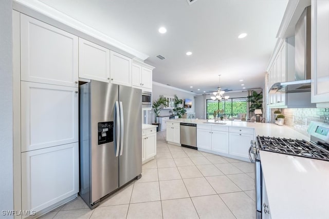 kitchen with kitchen peninsula, tasteful backsplash, stainless steel appliances, sink, and white cabinets