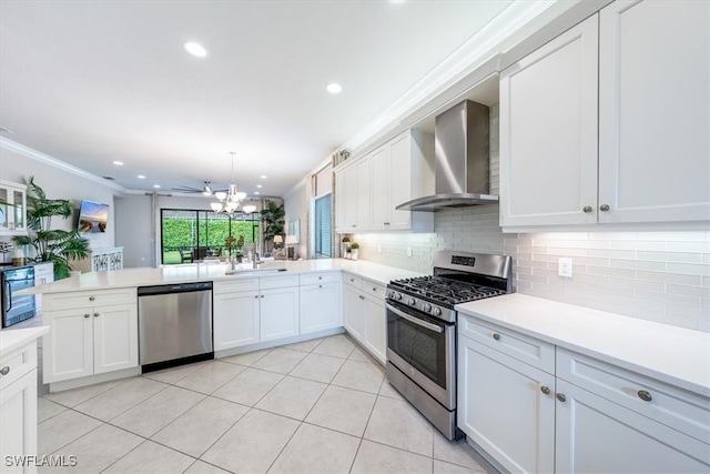 kitchen featuring white cabinets, wall chimney exhaust hood, crown molding, and stainless steel appliances