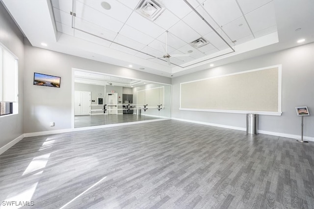 unfurnished room featuring a raised ceiling, ceiling fan, and wood-type flooring