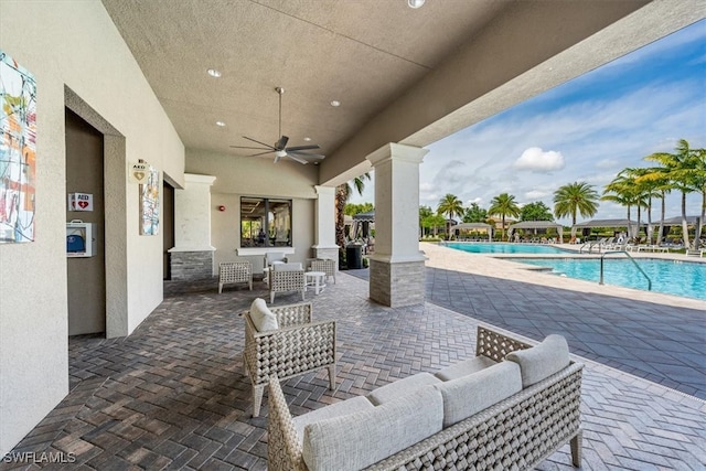 view of patio / terrace with an outdoor living space, ceiling fan, and a community pool