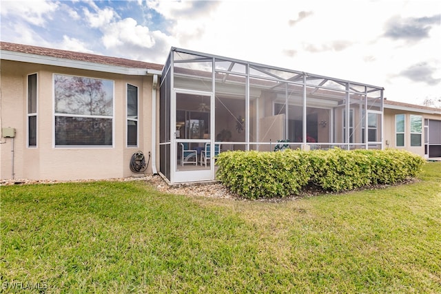 rear view of property with glass enclosure and a lawn