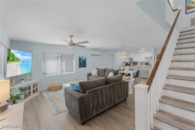 living room featuring ceiling fan, light wood-type flooring, and an AC wall unit