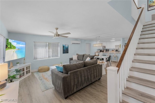 living room with ceiling fan, an AC wall unit, and light hardwood / wood-style floors