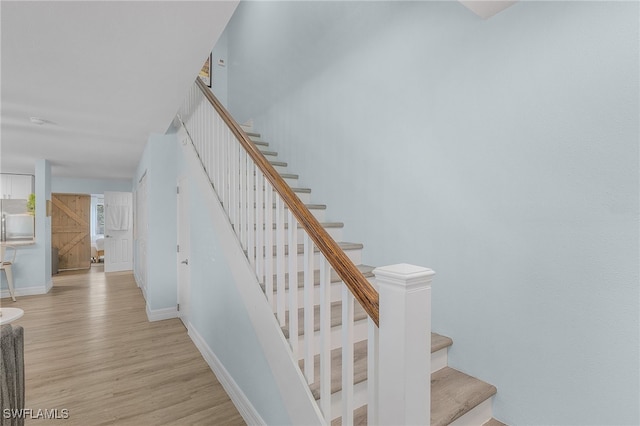 stairs featuring a barn door and hardwood / wood-style floors