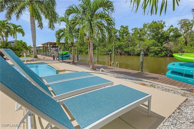 view of swimming pool featuring a water view, a patio, and a boat dock