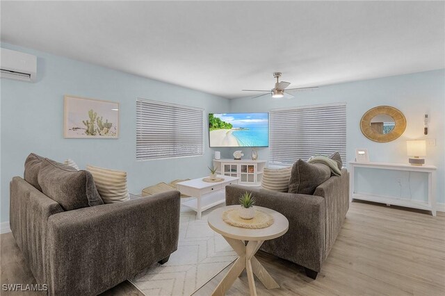 living room featuring a wall mounted AC, ceiling fan, and light wood-type flooring