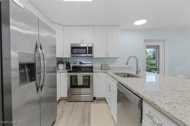 kitchen with white cabinetry, sink, stainless steel appliances, light stone counters, and light wood-type flooring