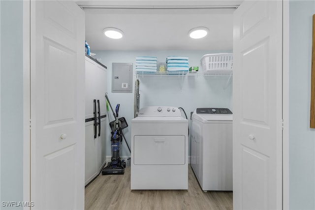 laundry room featuring light wood-type flooring, electric panel, and separate washer and dryer