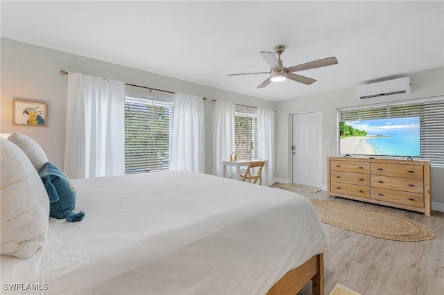 bedroom featuring a wall mounted AC, ceiling fan, and light hardwood / wood-style floors