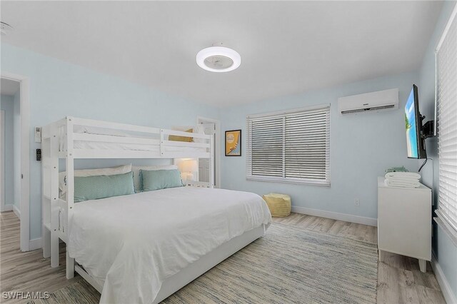 bedroom with an AC wall unit and light hardwood / wood-style floors