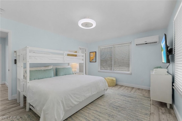 bedroom with light hardwood / wood-style flooring and a wall unit AC