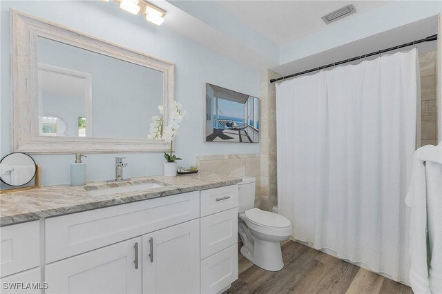 bathroom featuring a shower with shower curtain, vanity, toilet, and wood-type flooring