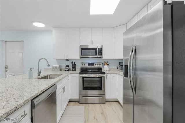 kitchen featuring stainless steel appliances, sink, white cabinets, and light stone counters