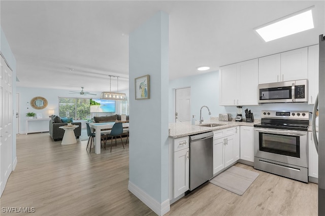 kitchen featuring sink, light hardwood / wood-style flooring, light stone countertops, appliances with stainless steel finishes, and white cabinetry