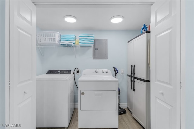 clothes washing area featuring washing machine and clothes dryer, electric panel, and light wood-type flooring