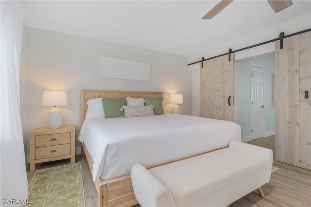 bedroom featuring a barn door, ceiling fan, and hardwood / wood-style flooring