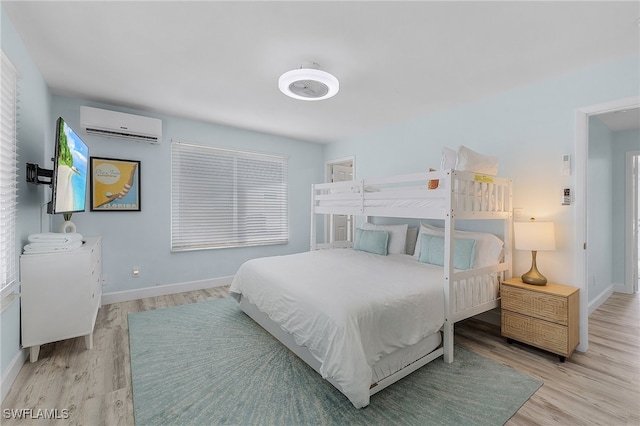 bedroom with light hardwood / wood-style floors and a wall mounted AC